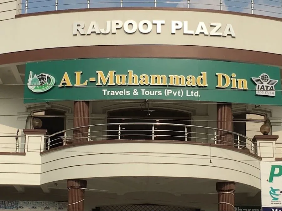 Rajpoot Plaza on Faisal Shaheed Road, with the AL-MUHAMMAD DIN Travels & Tours signboard above the first floor